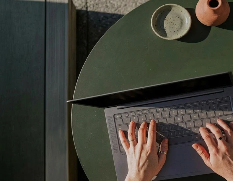Hands typing on a laptop at a café table, booking a discovery call